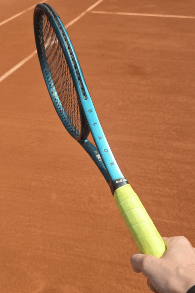 Jogador segurando a raquete Wilson Blade 98 durante teste em quadra de saibro. Babolat vs Wilson.