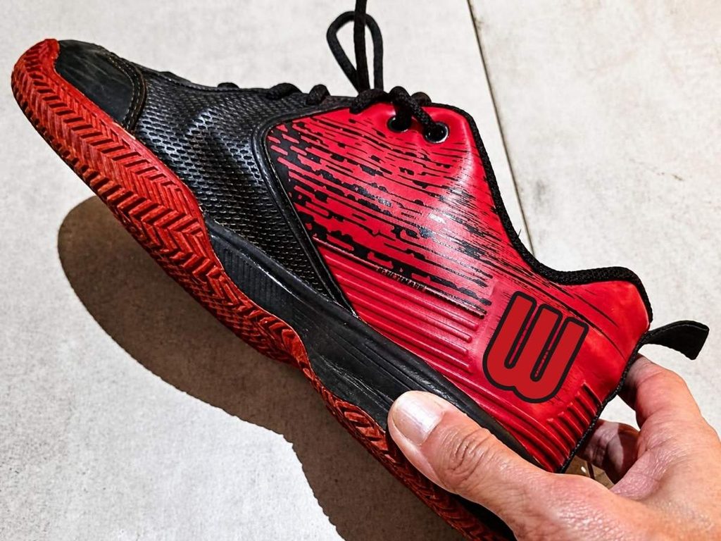 Tênis Wilson K Ultimate preto e vermelho com desgaste após uso prolongado.